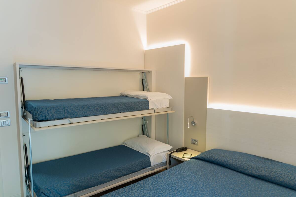 A bunk bed room with a desk and a mirror.