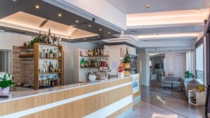 A modern bar area with wooden shelves stocked with bottles and glasses, a polished reception desk, and a clean, contemporary interior design. - Hotel Residence Mara (Jesolo)