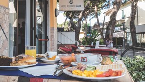 A breakfast table with various dishes, a sign for Hotel Residence Mara, and outdoor seating. - Hotel Residence Mara (Jesolo)