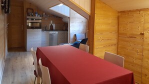 A compact kitchen with wooden walls and a dining area with a red table.