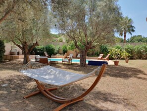 A hammock in a backyard with a pool, lounge chairs, and potted plants. - LA GRANDE PINÈDE (Sainte-Maxime)