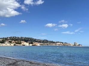 A coastal town with buildings along the shore and a clear blue sky. - LA GRANDE PINÈDE (Sainte-Maxime)
