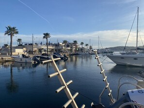 A marina with boats docked, palm trees, and a building with a balcony.