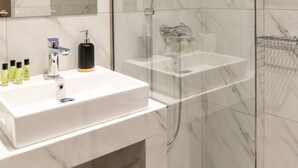 Een moderne badkamer met een wit marmeren wastafel, een glazen douchecabine en een grote spiegel.