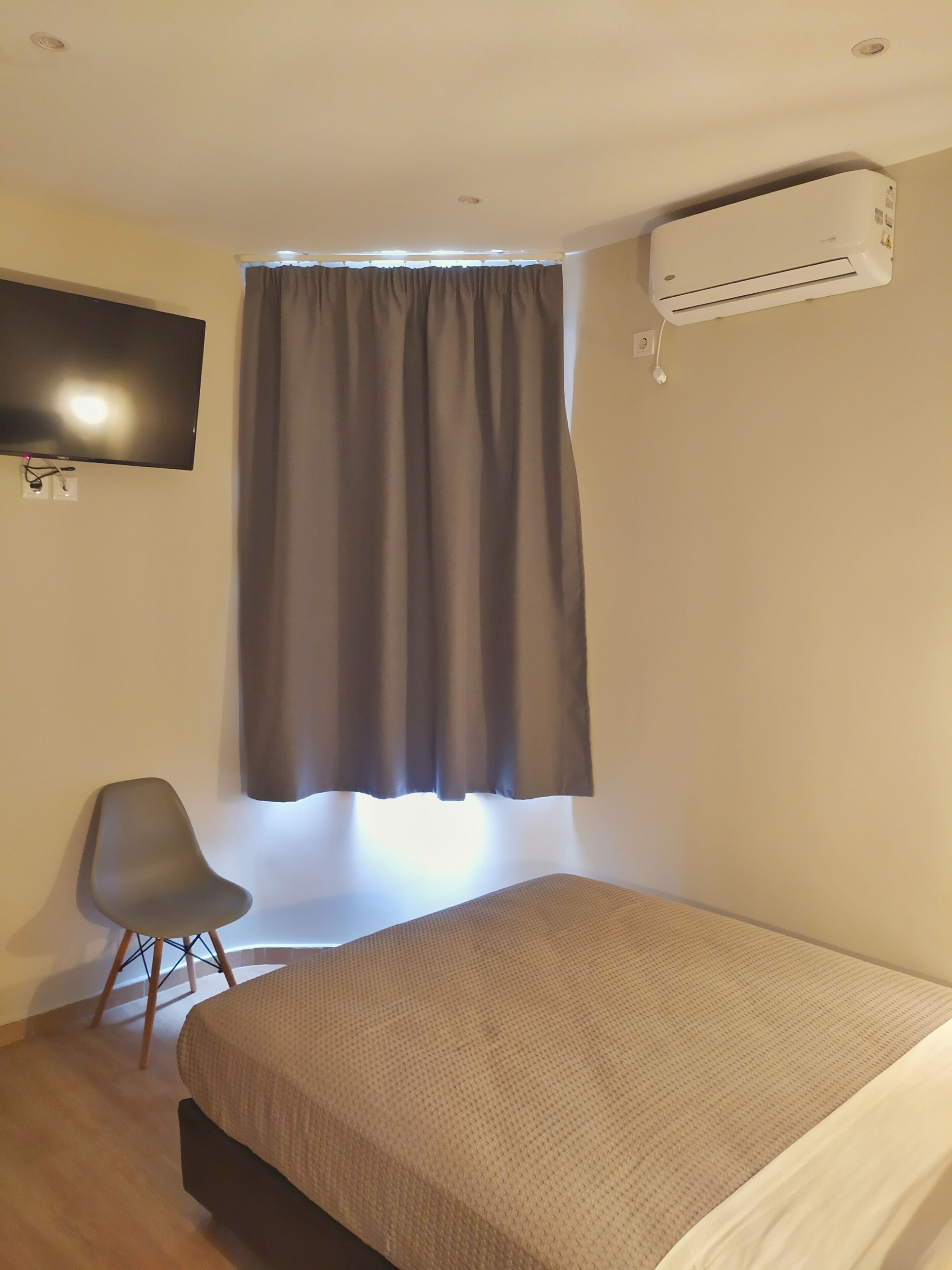 Een kamer met een bed, een stoel, een televisie en een airconditioning.