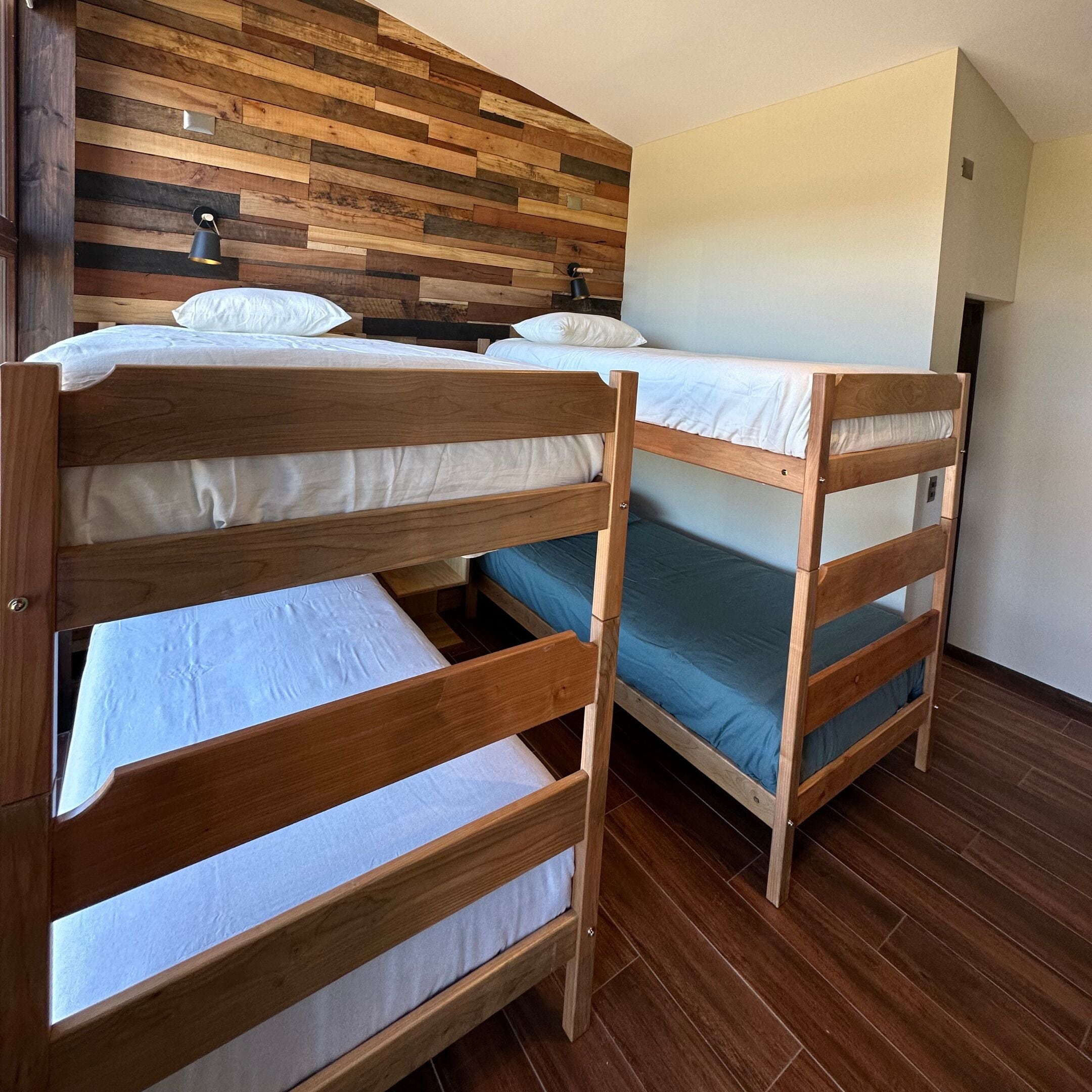 A room with two bunk beds, wooden walls, and a tiled floor.