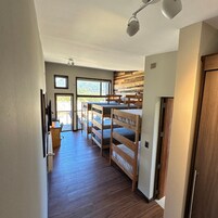 Quarto com beliches, uma mesa de estudo e janela com vista para o exterior.