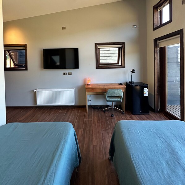 A hotel room with two beds, a desk with a chair, a television, a heater, and a window with blinds. - Nativa Mountain Suites (Curacautin)