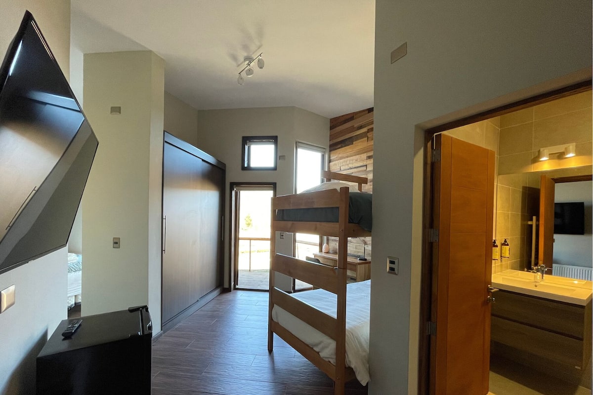 Ein Schlafzimmer mit Etagenbett, Schreibtisch und Kleiderschrank.