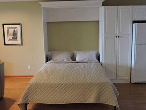 A bedroom with a bed, a wardrobe, and a framed picture on the wall.