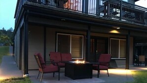 Um pátio externo com uma lareira, cadeiras vermelhas e uma mesa.
