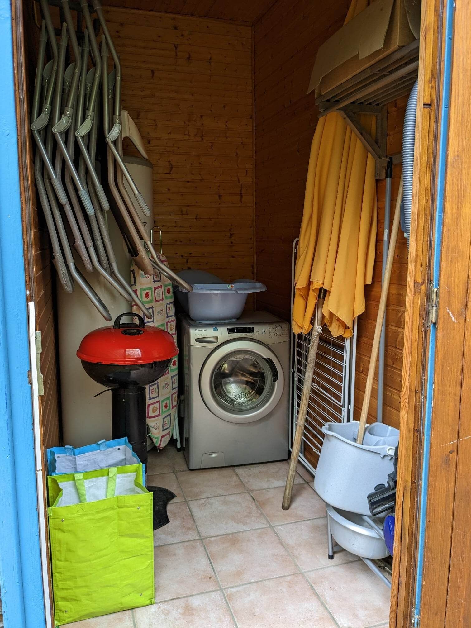 Une buanderie équipée d’un lave-linge, d’une cuisinière à gaz rouge et de divers outils de nettoyage.