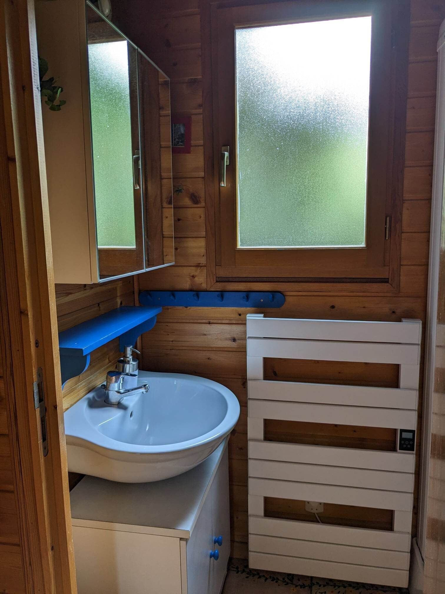 Un baño pequeño con un lavabo blanco, un espejo y un ventanal esmerilado.