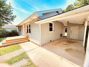 Ett enplanshus med en inglasad veranda, en liten trädgård framför huset och ett garage.