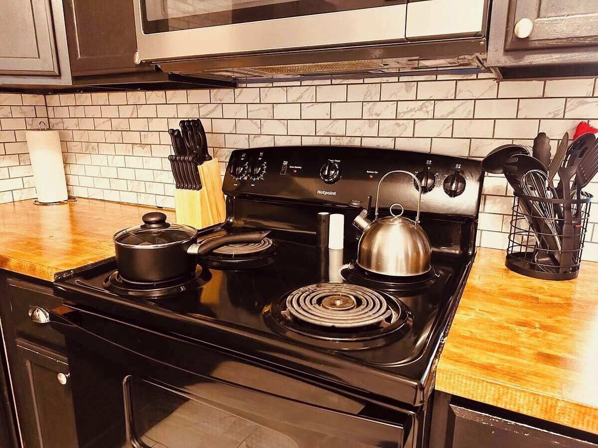 A kitchen with a black stove, a kettle, and a pot on the burners.
