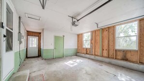 Una stanza con pavimento in cemento, una porta verde e rivestimenti in legno sulle pareti.