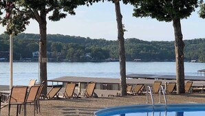 Un área de piscina con sillones de descanso y vistas a un lago.
