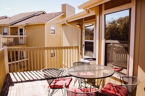 En uteplats med utemöbler, en skjutdörr i glas och utsikt över ett hus i närheten.