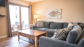 Olohuoneessa on harmaa sohva, puinen sohvapöytä ja seinällä taulu.