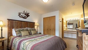 A bedroom with a large bed, wooden headboard, and a decorative wall piece. - Panoramic Mountain Views/Hot Tub Access/Private Deck with Grill (Keystone)