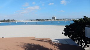 Ein Strand mit blauem Himmel, Booten und einem Gebäude in der Ferne.