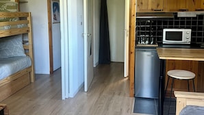 Une pièce de taille modeste comprenant un coin cuisine, des meubles en bois et un lit.
