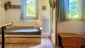 Une chambre à coucher avec un lit, un radiateur, une fenêtre et un bureau en bois.