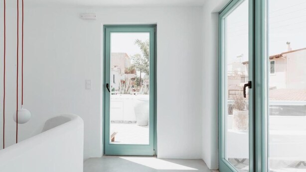 A modern room with a large window, a door leading outside, and a white bathtub.