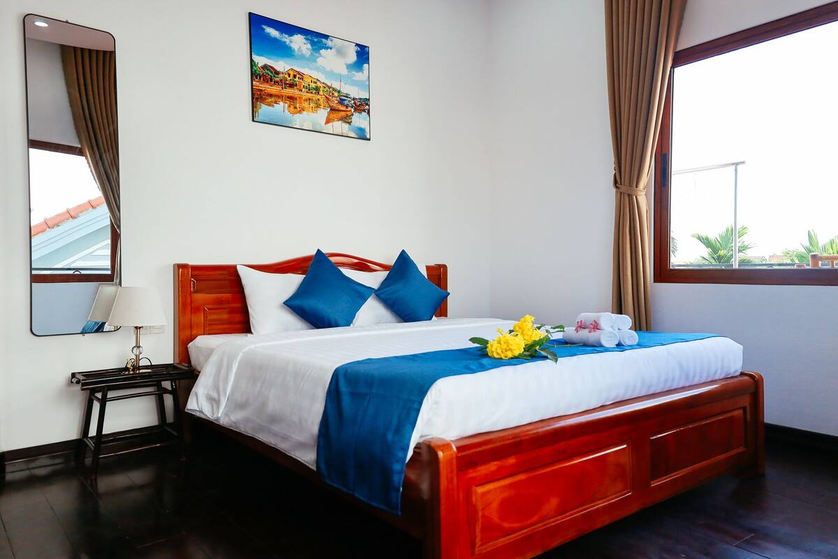 A neatly made bed with blue and white bedding, a wooden headboard, and a blue throw blanket.