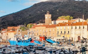 Una marina con barche ormeggiate, una torre dell'orologio e edifici con insegne.