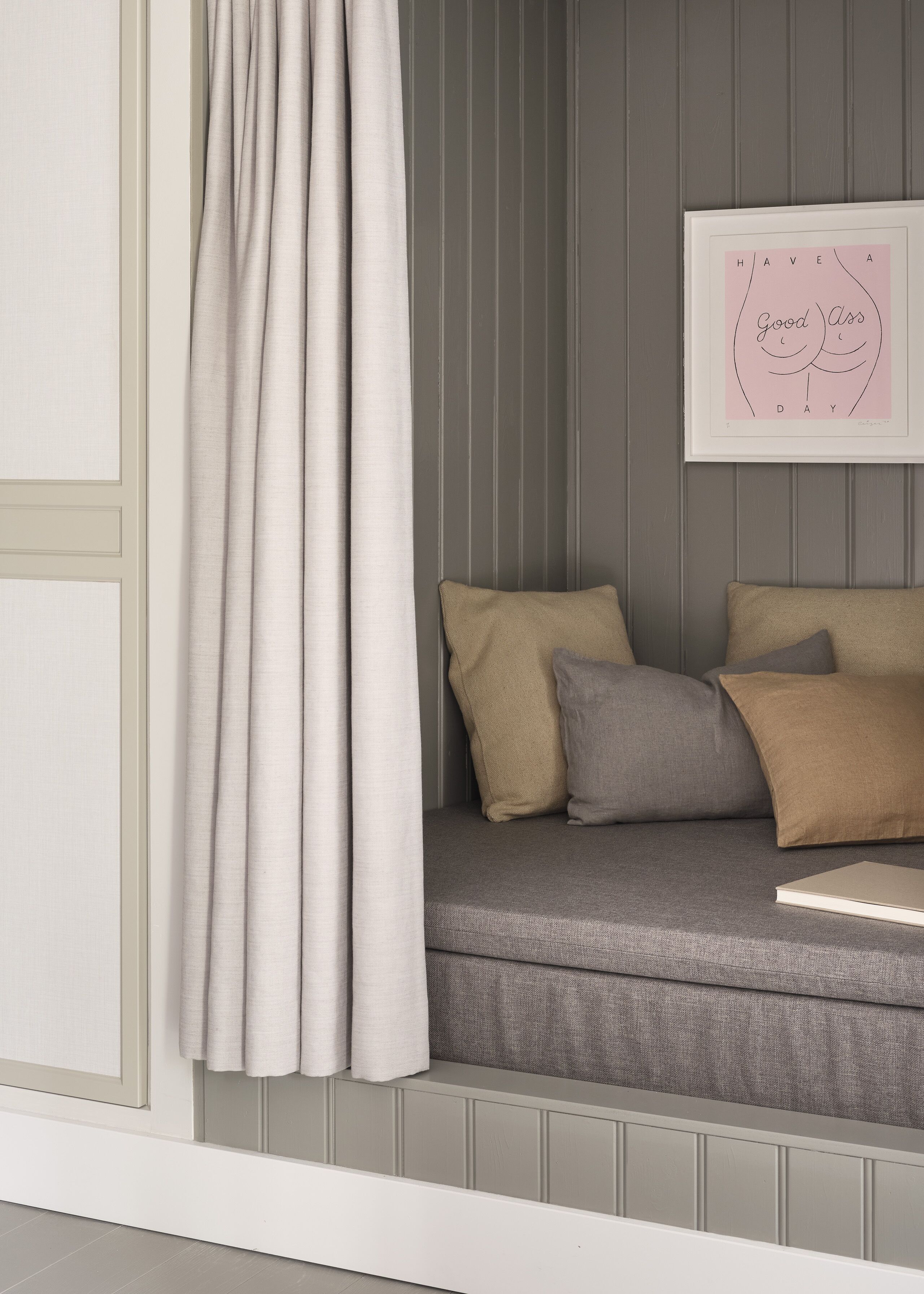 Un coin salon accueillant avec un canapé gris, des coussins beige et gris, et une citation inspirante encadrée accrochée au mur.