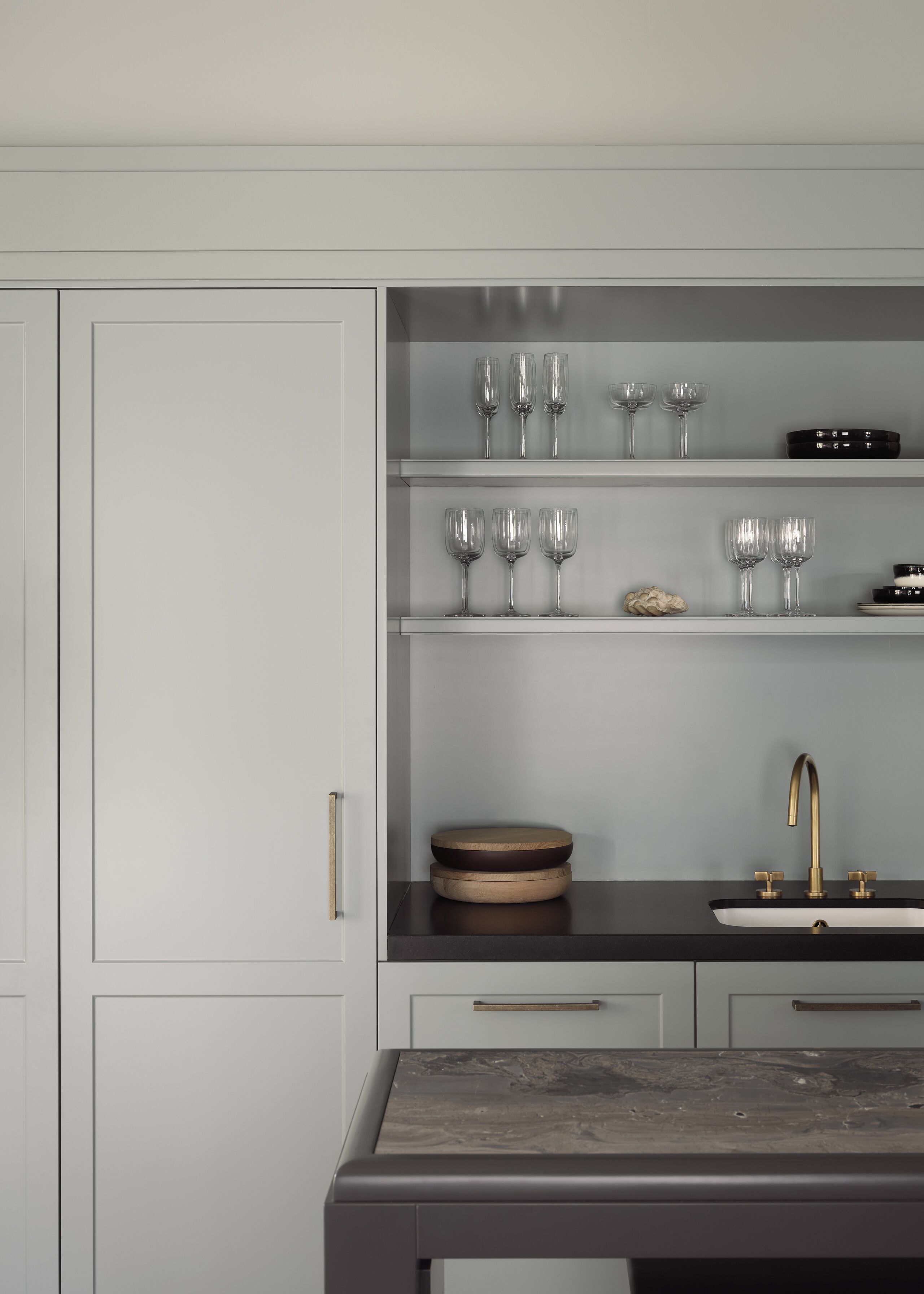 Une cuisine moderne avec des meubles blancs, un plan de travail noir et un robinet doré.