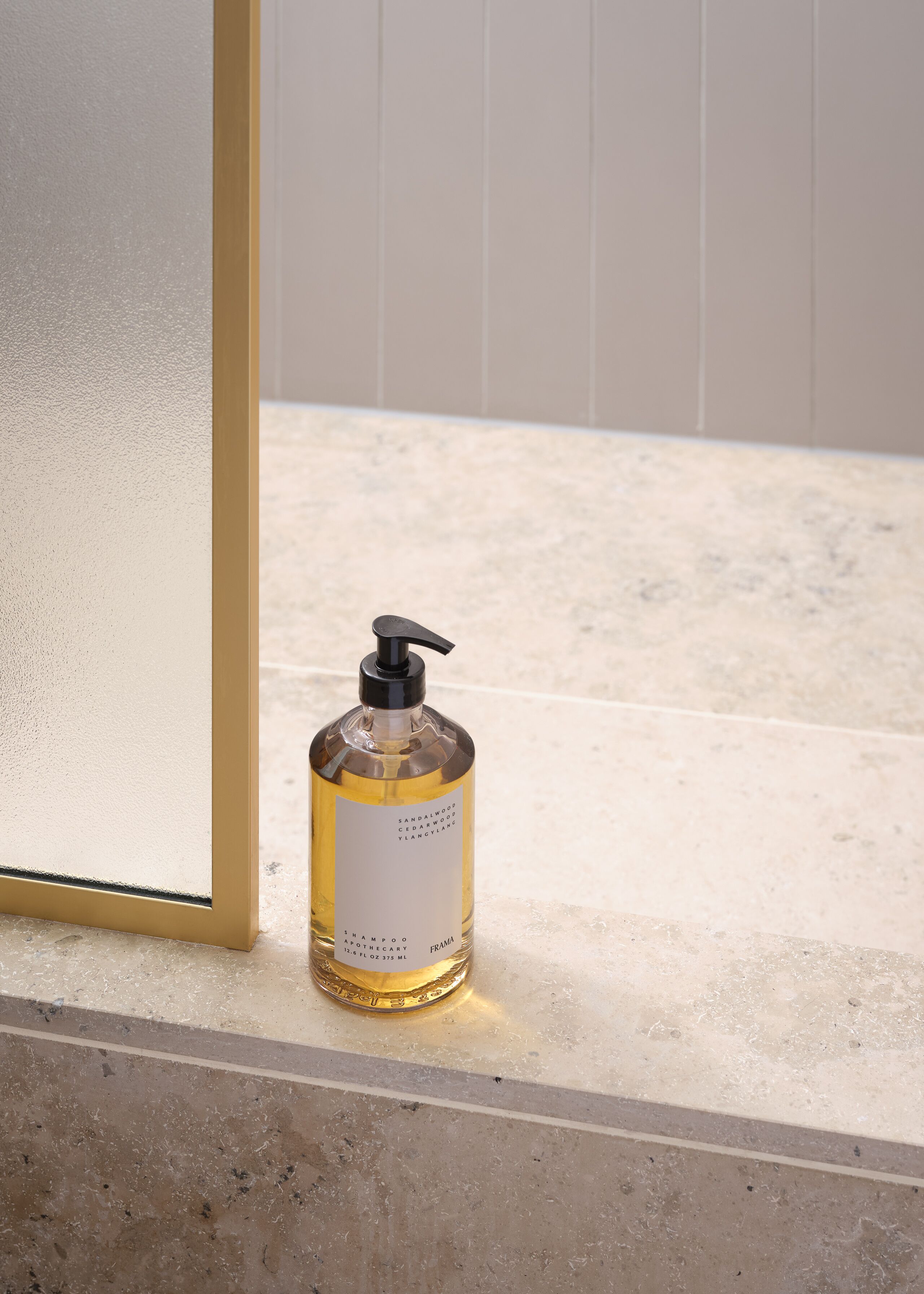 A bathroom with a marble floor and a glass shower enclosure.