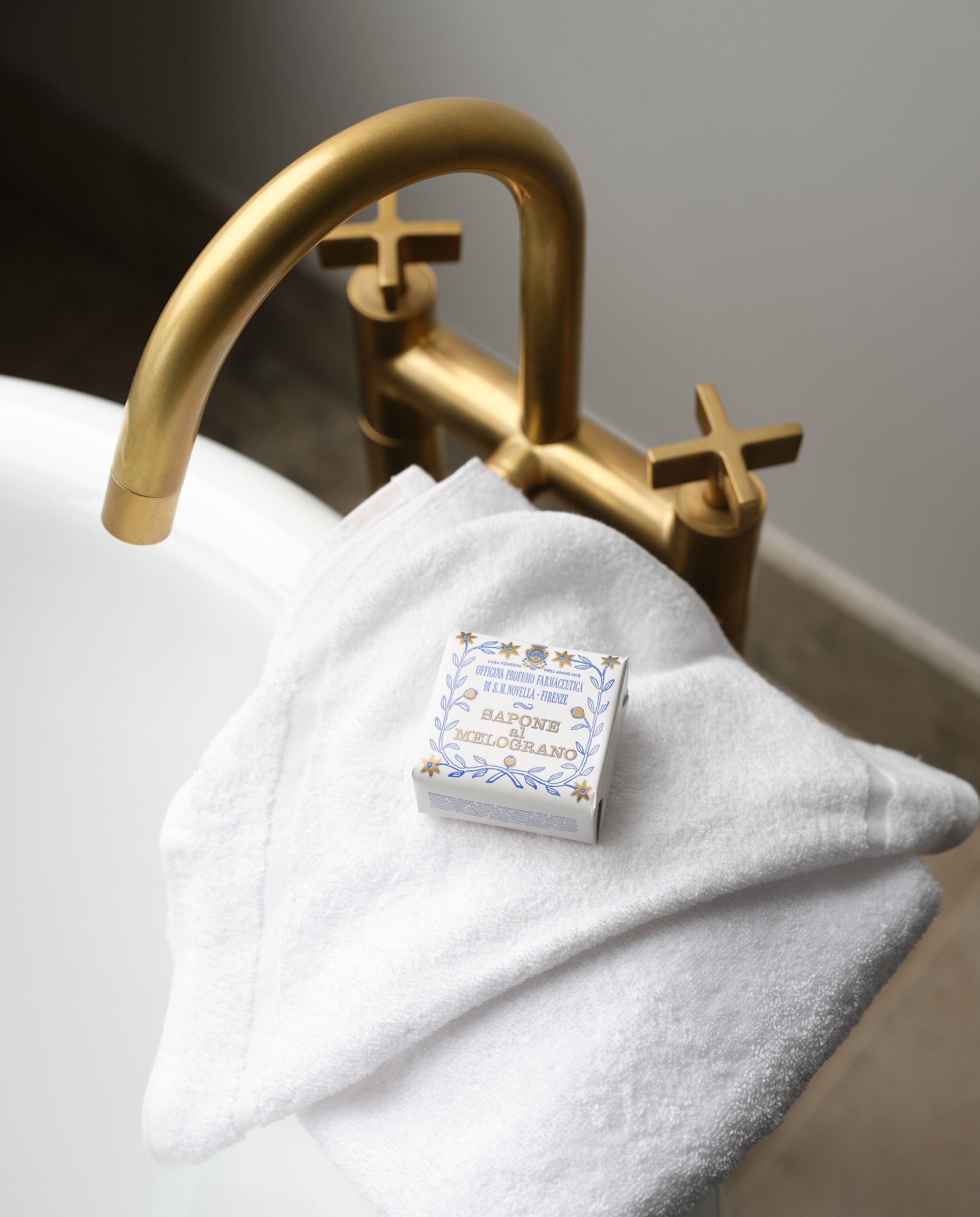 Une salle de bain avec un robinet doré et une serviette blanche suspendue à un porte-serviettes.
