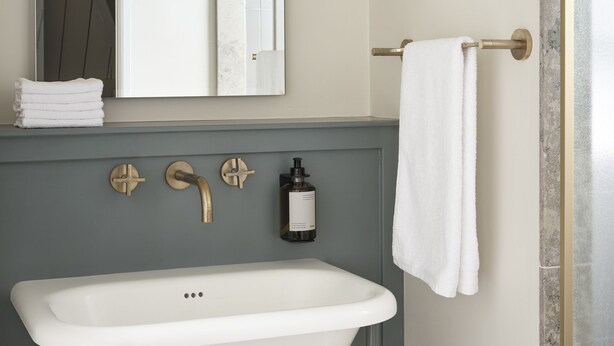 A bathroom with a white sink, a mirror, a towel rack, and a bottle of liquid soap. - Benedict Noordwijk (Noordwijk)