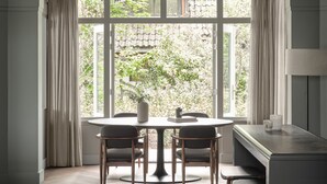 Un salón moderno con un ventanal grande, una mesa redonda y taburetes de bar.