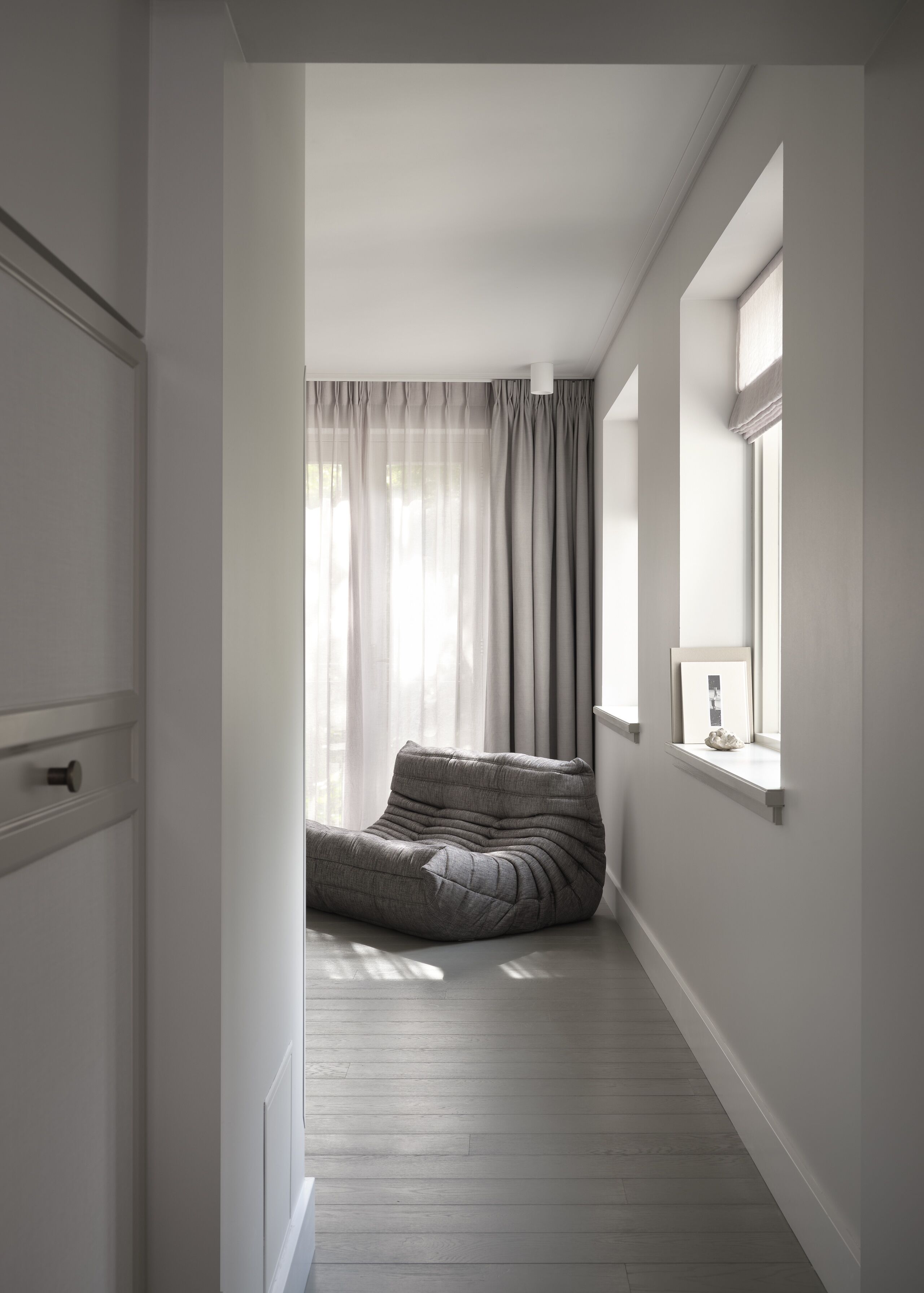 Ein schmales Entree mit integrierter Sitzecke, einem Fenster mit Aussicht und einer Tür links.