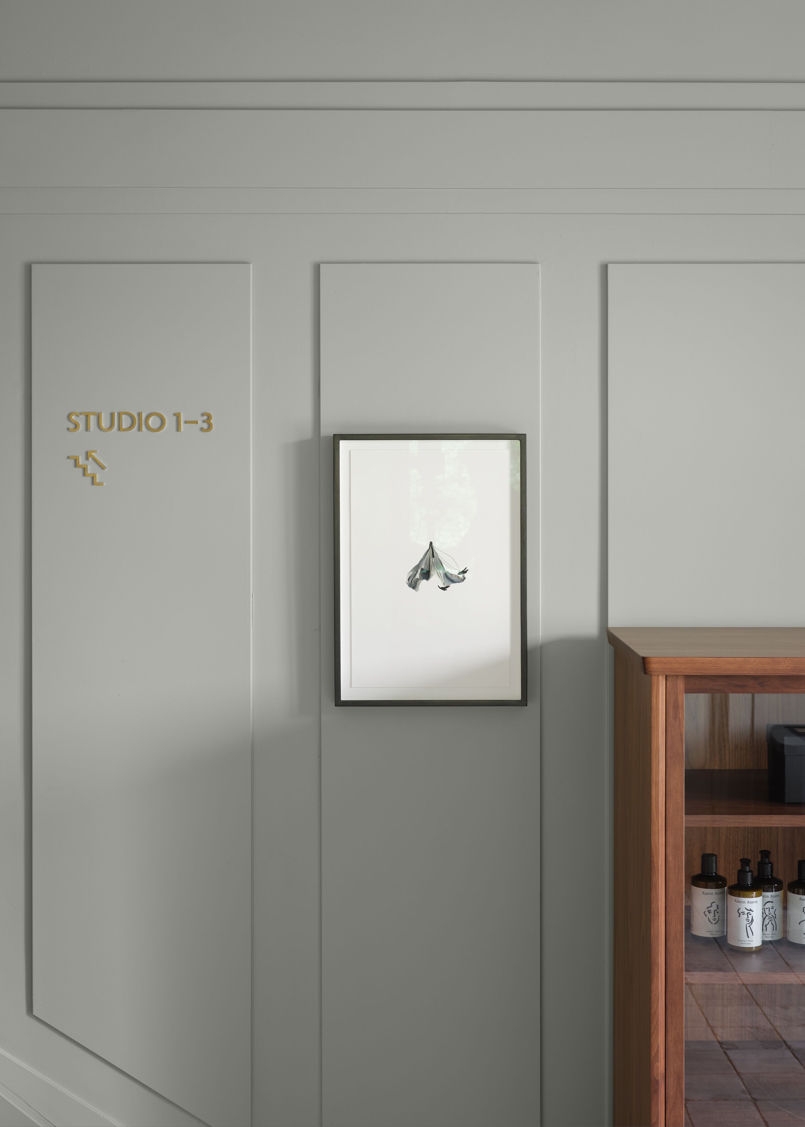 Una pared con una obra de arte enmarcada y un letrero que dice "STUDIO 1-3".