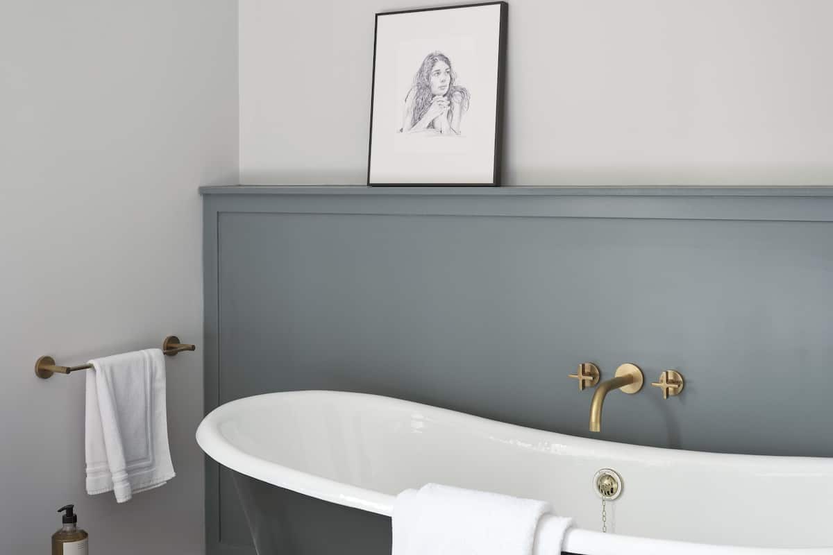 Ein modernes Badezimmer mit einer freistehenden Badewanne, einem kleinen hölzernen Hocker und einer Weinflasche auf dem Boden.