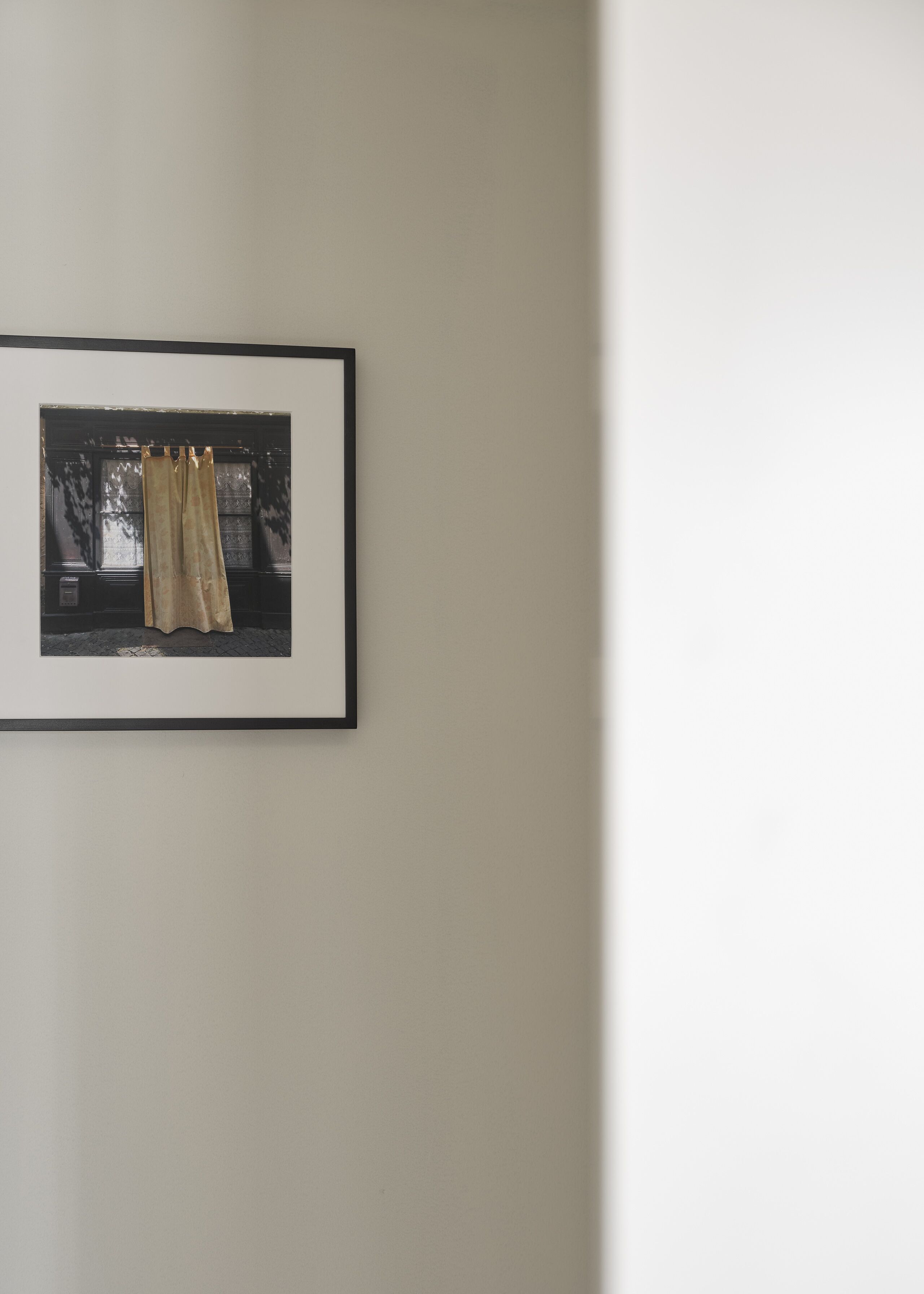 Fotografía enmarco de una ventana con cortinas sobre una pared lisa.