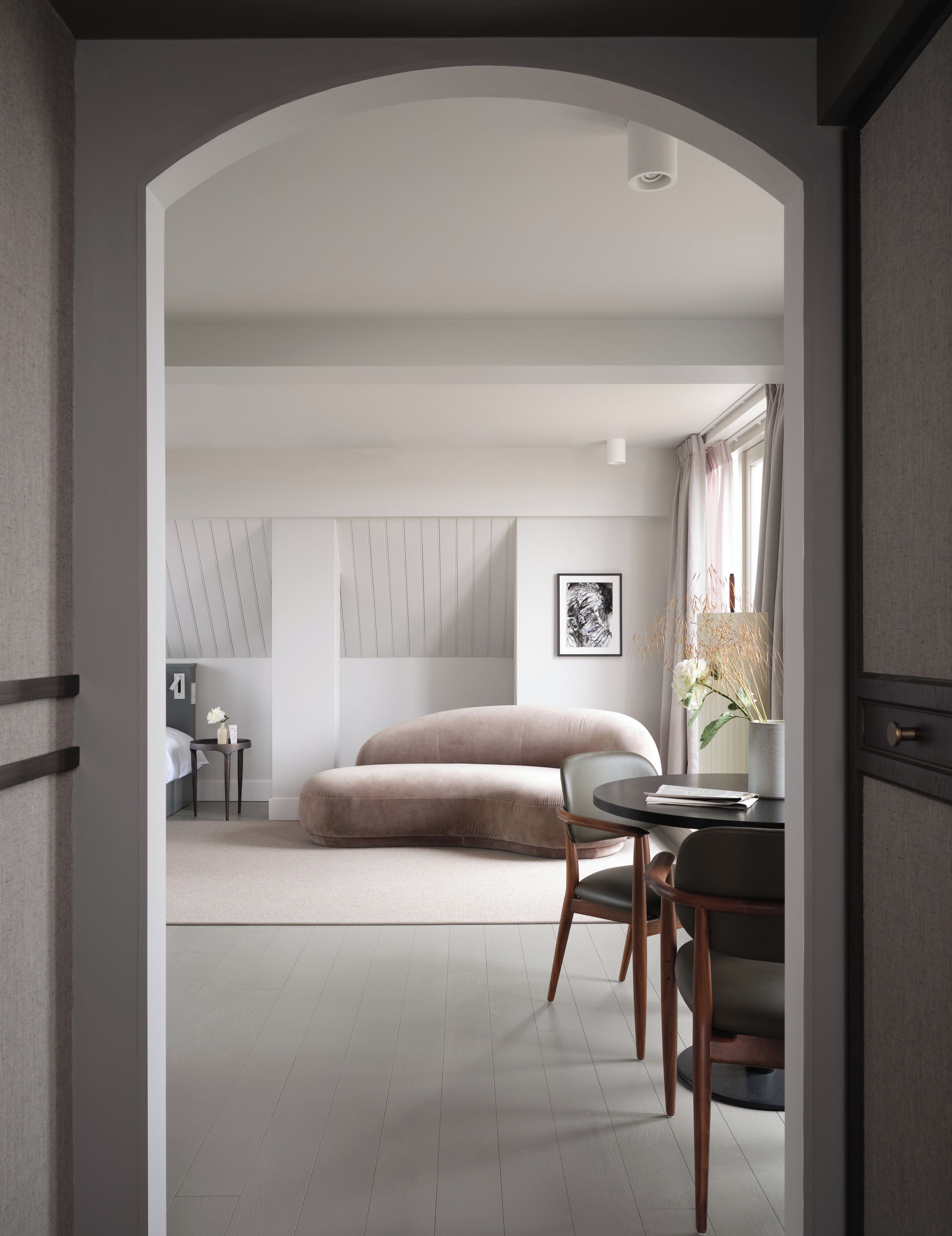 Un appartement de luxe moderne, doté d’un design minimaliste, comprenant un canapé, une table à manger et une œuvre d’art encadrée au mur.