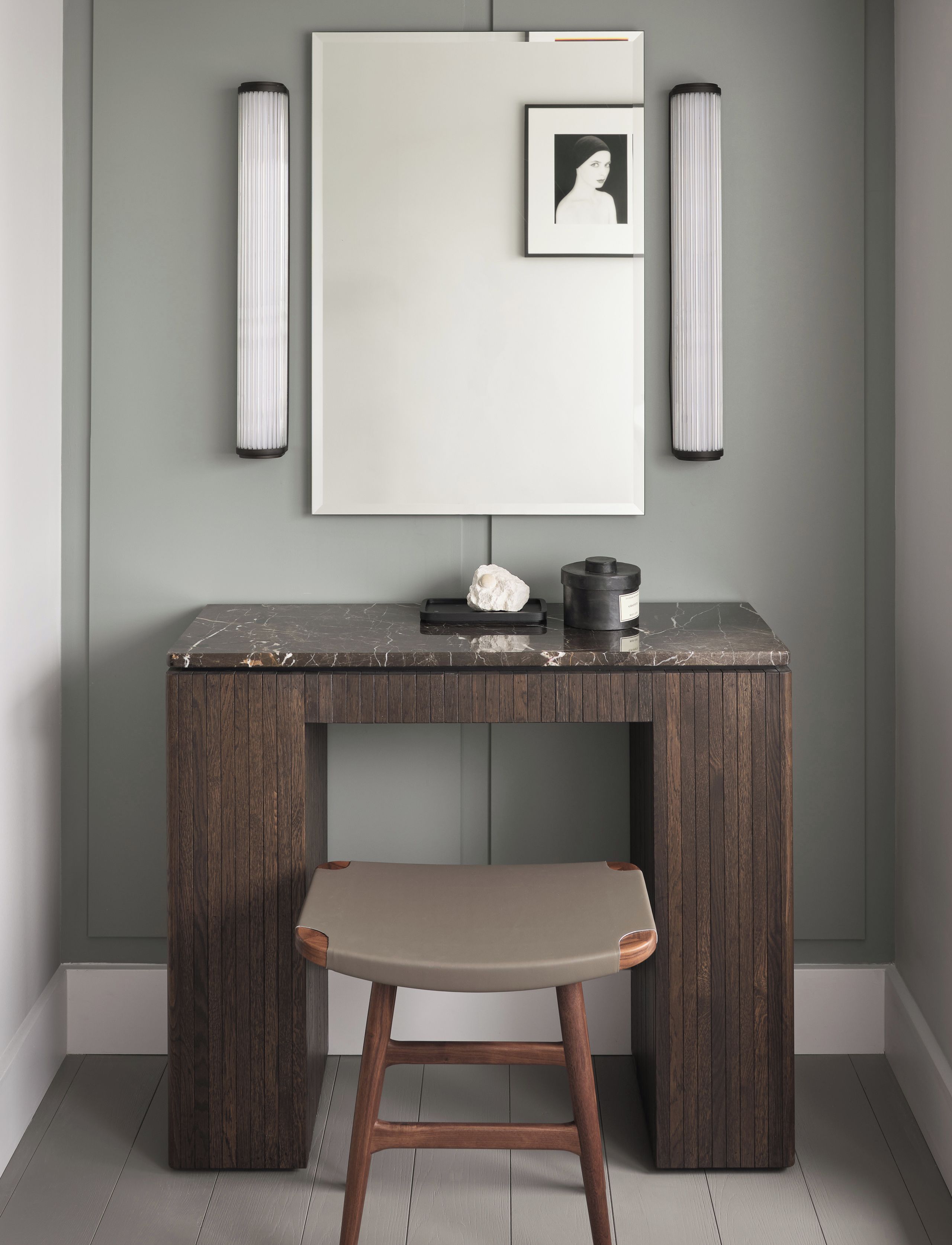 A modern, minimalist room with a dark wooden desk, a cushioned bench, and framed artwork on the wall.