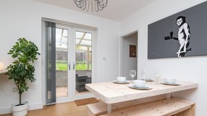 A modern kitchen with a wooden table set for dining, a potted plant, and a sliding glass door leading to a backyard. - Newly Refurbished Gem | Perfect | Alexa | Sleeps 5 (Bristol)