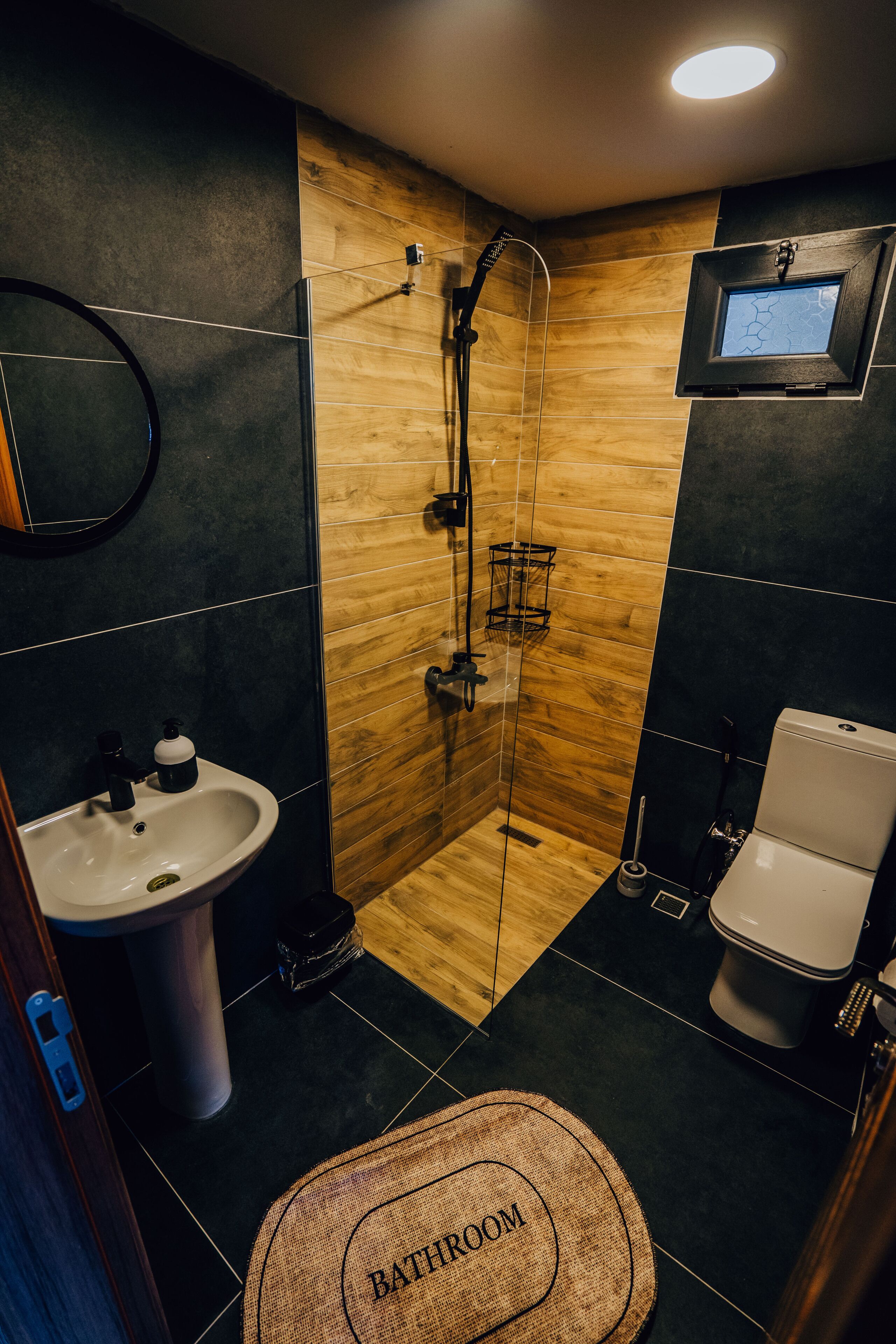 A modern bathroom with a glass-enclosed shower, a sink, and a toilet.