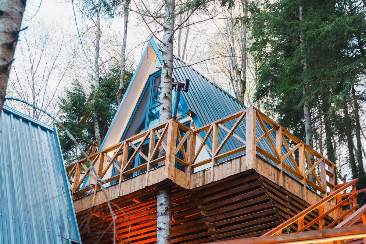 Una cabaña de madera con balcón, rodeada de árboles.