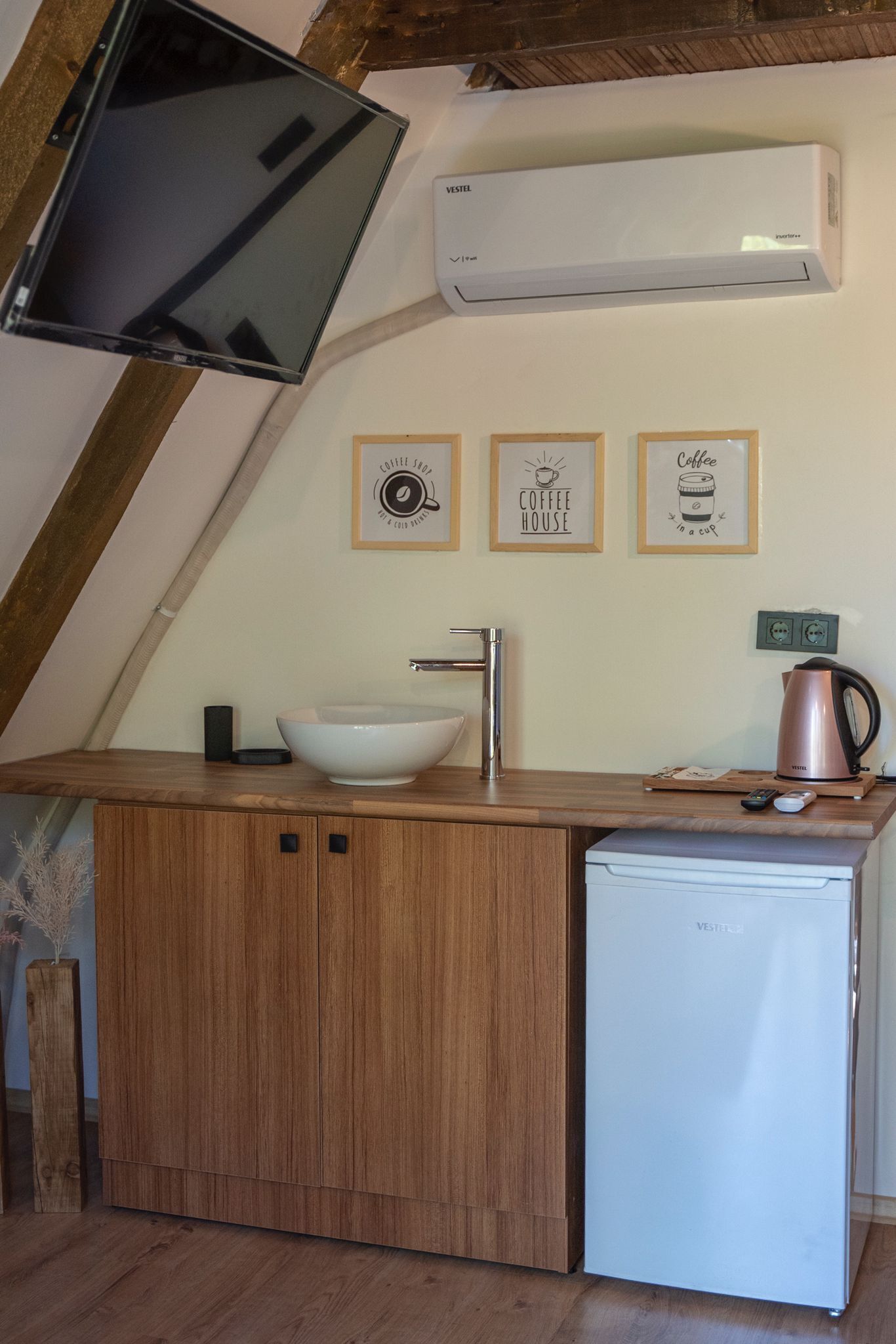A compact kitchen with a wooden countertop, a white sink, a coffee maker, and a small refrigerator.
