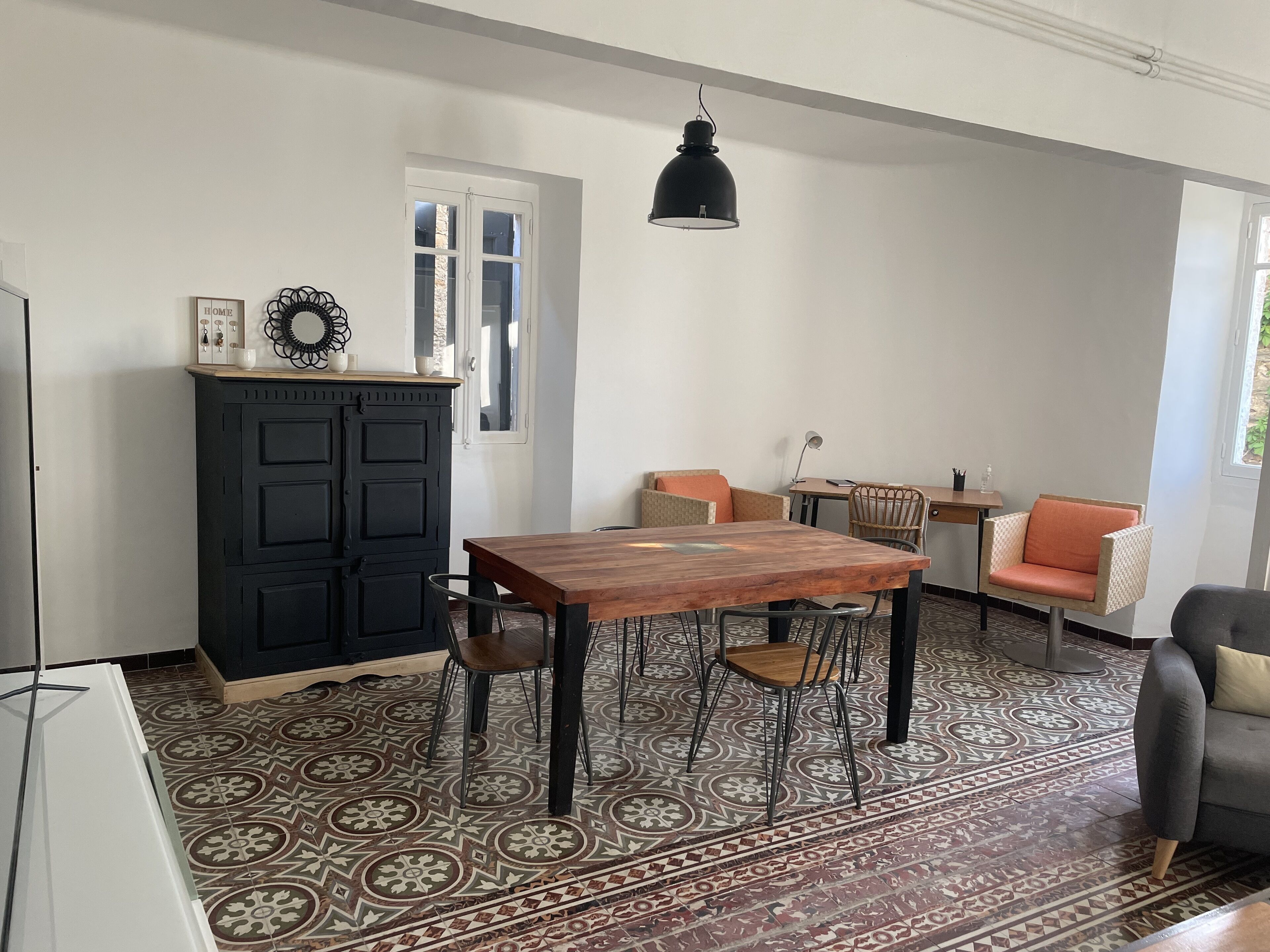 Un coin repas avec une table et des chaises en bois, un meuble noir et une suspension.