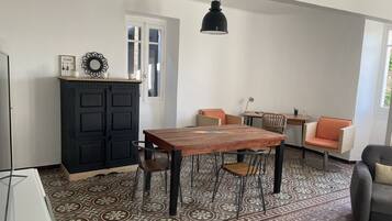 Un coin repas avec une table et des chaises en bois, un meuble noir et une suspension.