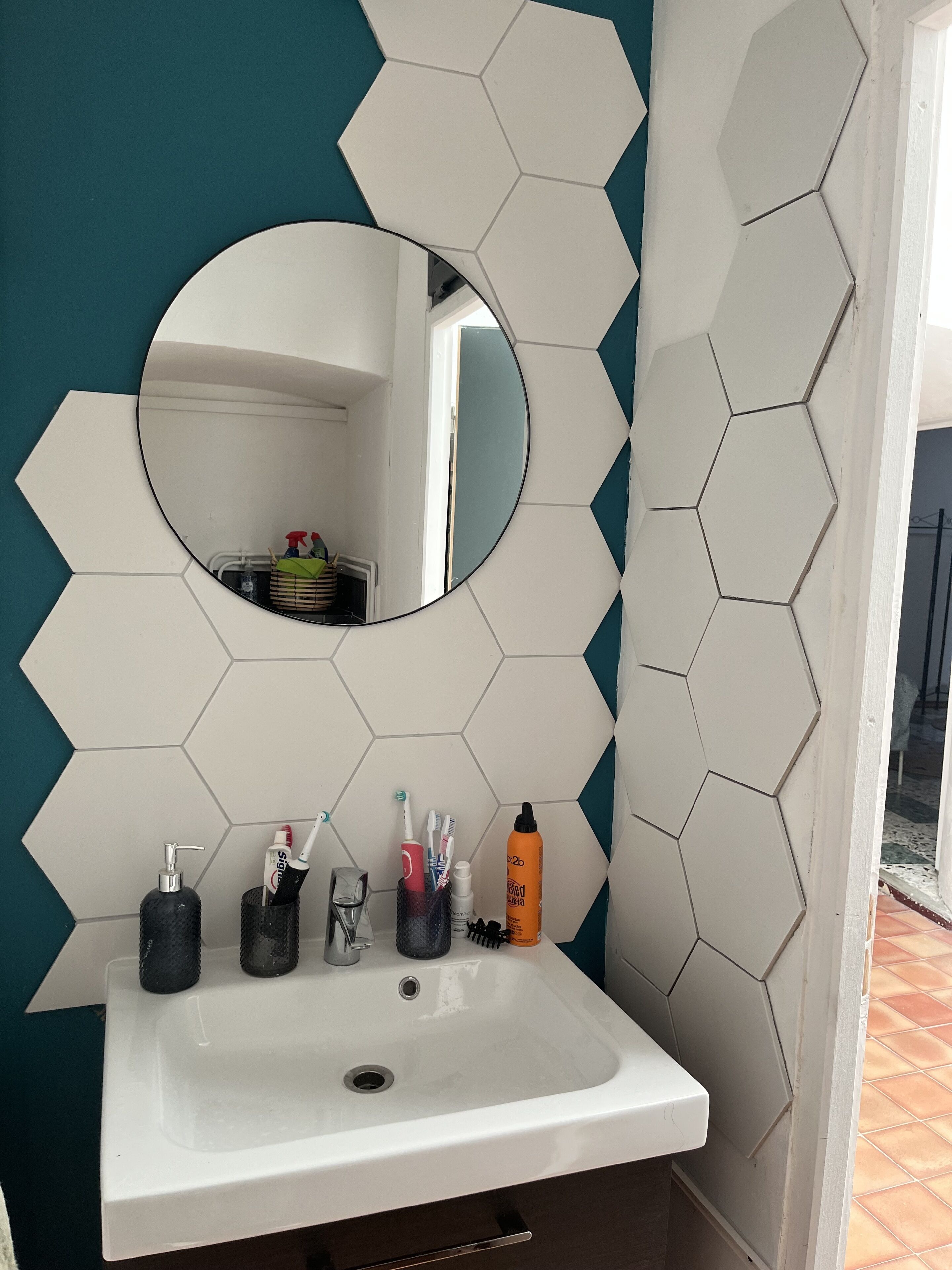 Un bagno con un lavandino bianco, uno specchio e articoli da toilette.
