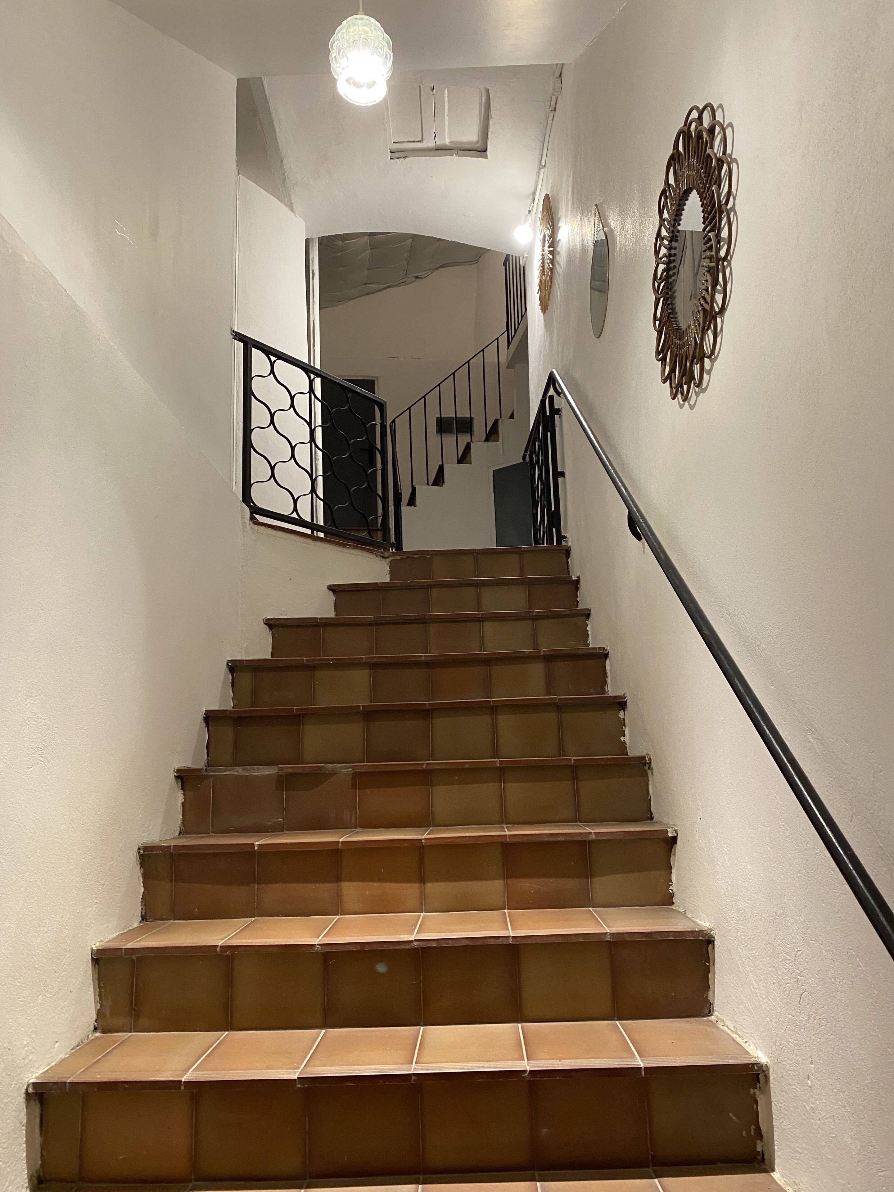 A staircase with brown tiles, a black handrail, and a decorative wall piece.